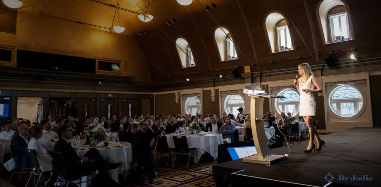 Female keynote speaker presenting to a corporate audience during a hybrid event in Sydney
